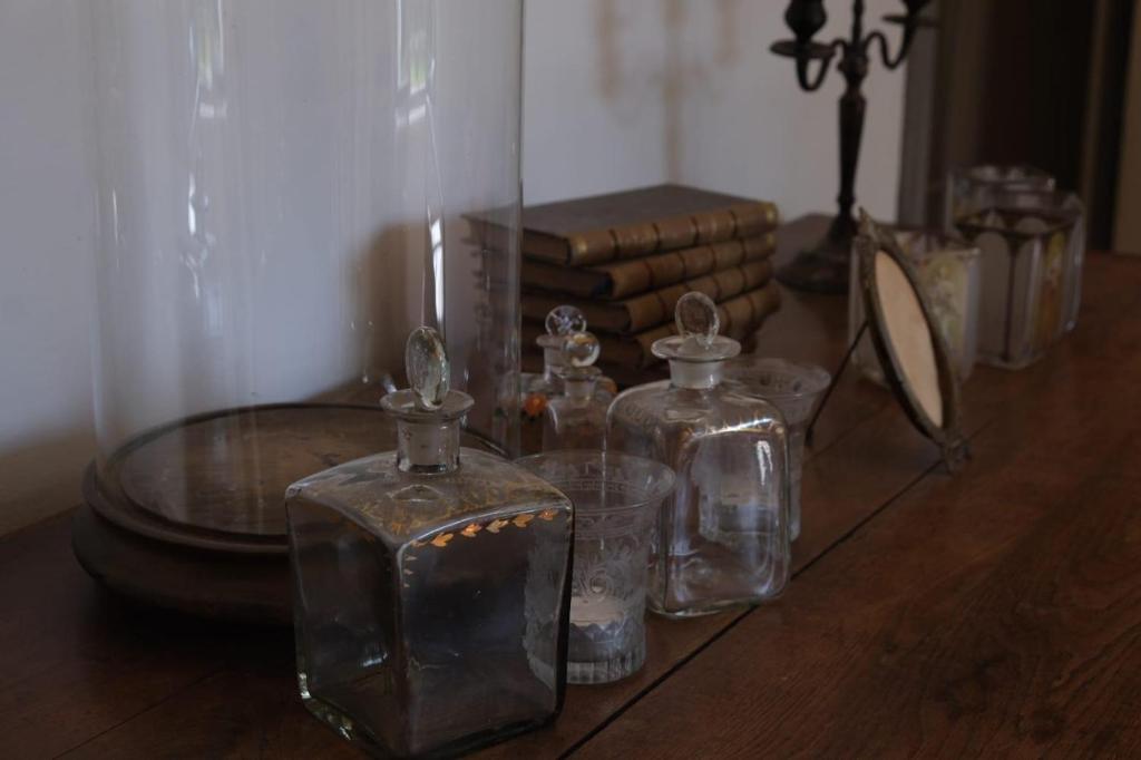 a table with glass containers and a mirror and books at L’hors-du temps in Le Tartre