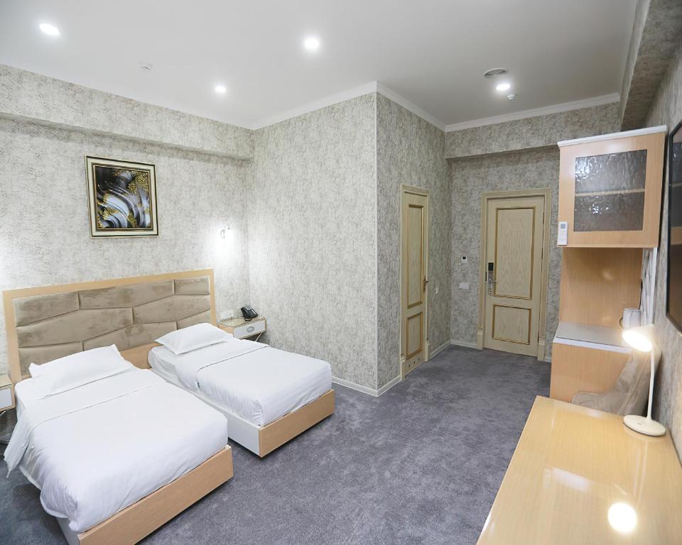 a hotel room with two beds and a desk at Reikartz Amirun Tashkent in Tashkent