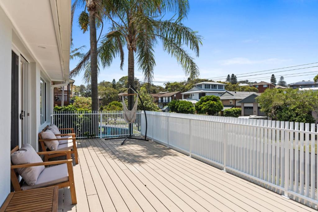 a deck with a hammock and palm trees on a house at Exquisite Beachside Luxury Resort Style Pool in Wamberal North