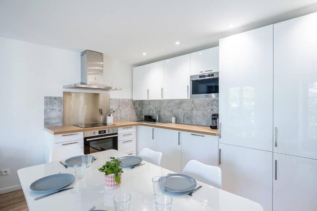 a kitchen with white cabinets and a white table and chairs at Le Grimont - 5 min de DisneyLand Paris in Coupvray