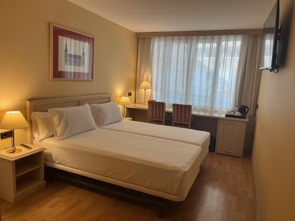 a bedroom with a bed and a desk and a window at BYPILLOW Castellana in Madrid