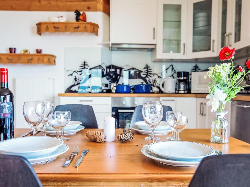 Una mesa de madera con platos y copas de vino encima. en Apartment Le Bristol A52 by Interhome, en Villars-sur-Ollon
