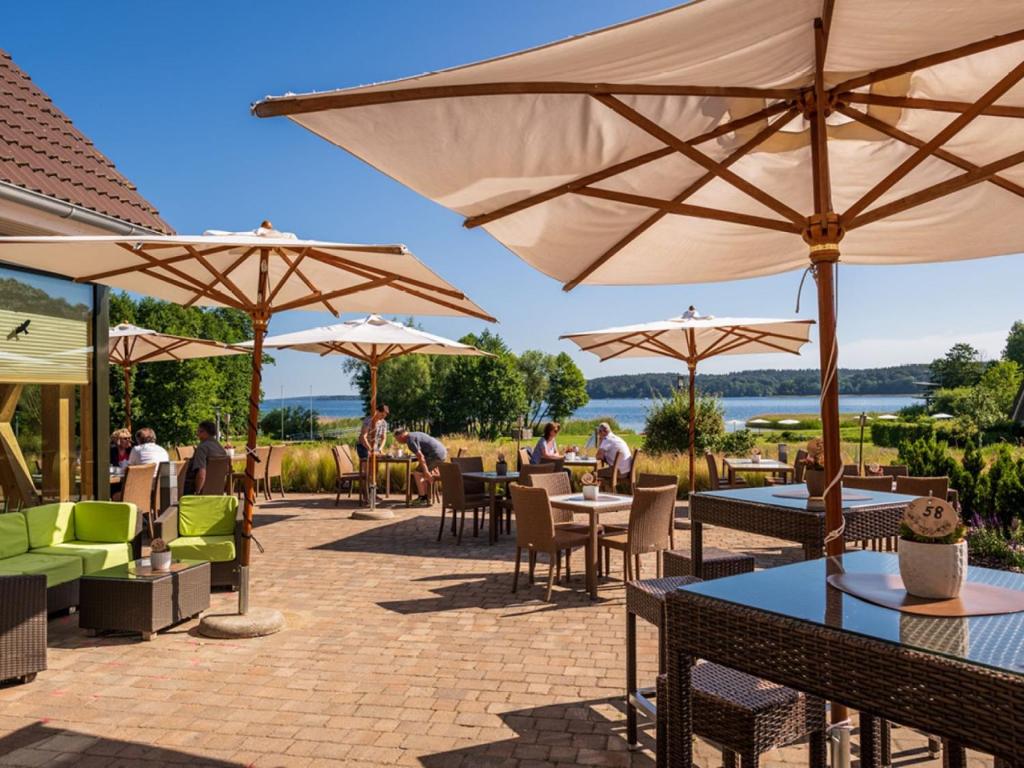 a patio with tables and chairs and umbrellas at Apartment Beech Resort Plauer See by Interhome in Ganzlin