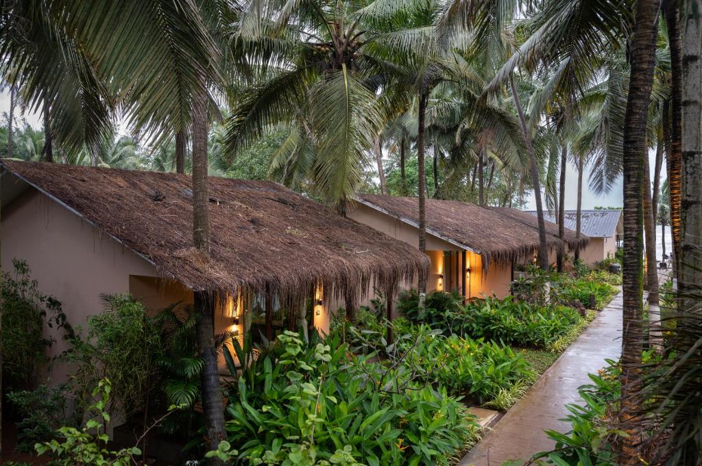 a resort with a thatched roof and palm trees at Palma Beach Resort in Mandrem