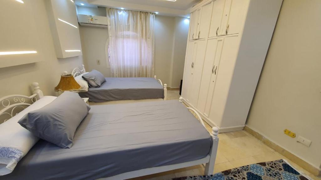 a bedroom with two beds and a cabinet at شقة فاخرة لعائلة بالمهندسين in Cairo