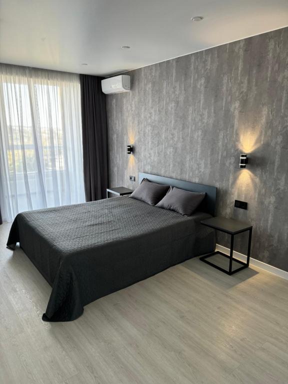 a bedroom with a large bed with a gray wall at Люкс Апартаменты Gray Pearl на Подолье in Vinnytsya