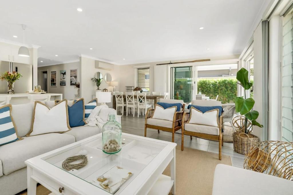 ein Wohnzimmer mit einer weißen Couch und einem Tisch in der Unterkunft Oscar's Broulee Beach Luxury Coastal Living in Broulee