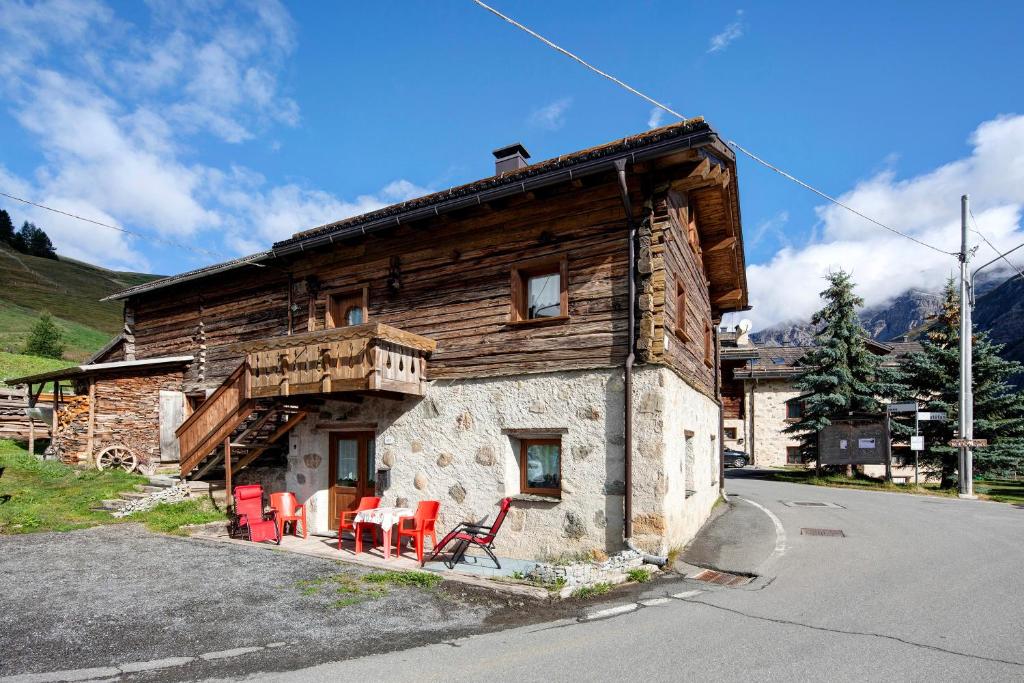 eine Blockhütte mit roten Stühlen davor in der Unterkunft Sole tra le Cime - Trepalle in Livigno