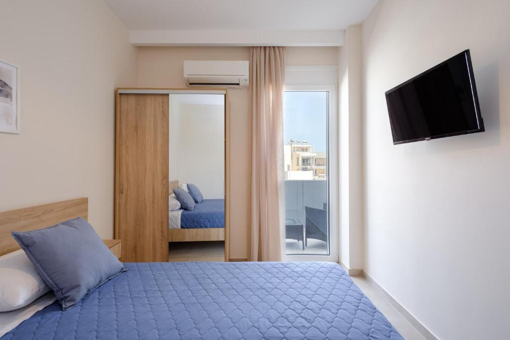 a bedroom with a blue bed and a television at Pietra Sole Suites in Ierapetra