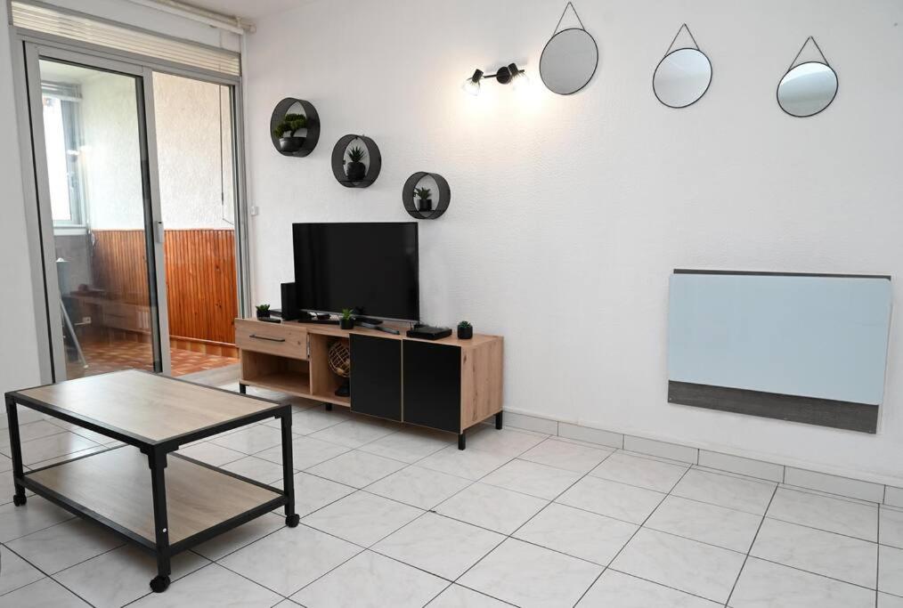 un salon avec une télévision à écran plat et une table dans l'établissement Charmant studio cabine avec parking, à Fréjus