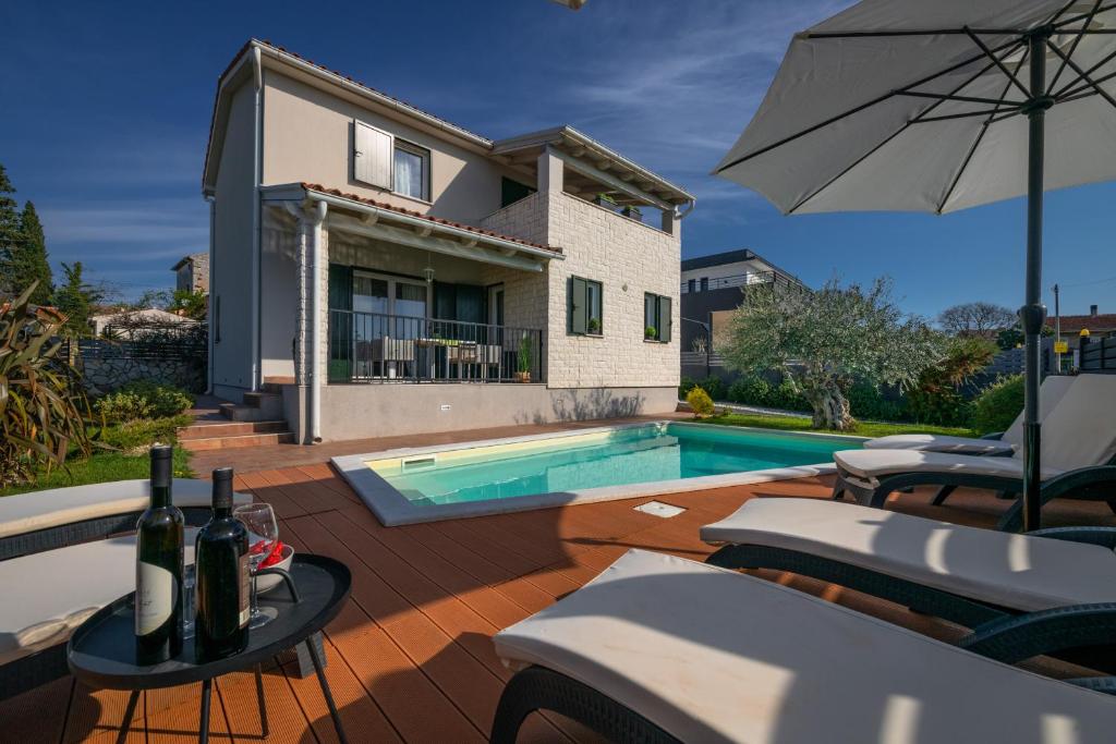 une maison avec une piscine et un parasol dans l'établissement Villa Laura Krnica near Pula for 8 people - pet friendly with children playground, à Krnica