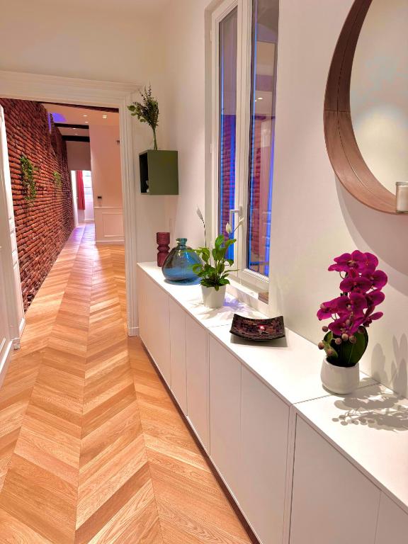 un couloir avec des armoires blanches et des fleurs violettes dans des vases dans l'établissement Appartement au cœur de Toulouse, à Toulouse
