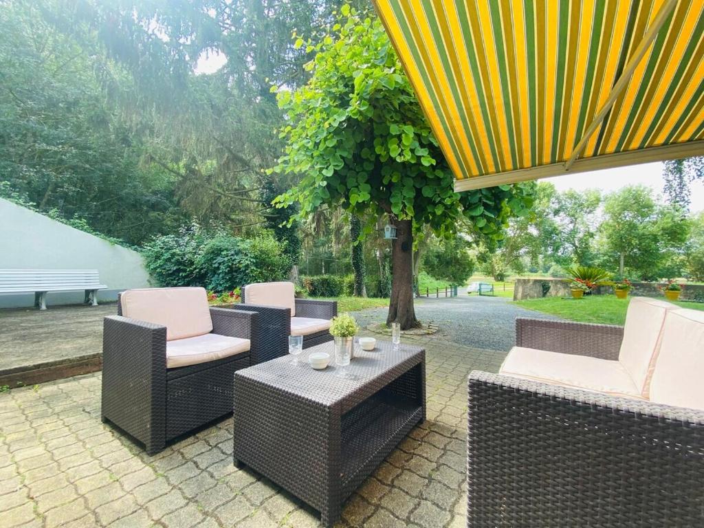 d'une terrasse avec des chaises en osier, une table et un arbre. dans l'établissement Casa Rivage, à Chalonnes-sur-Loire