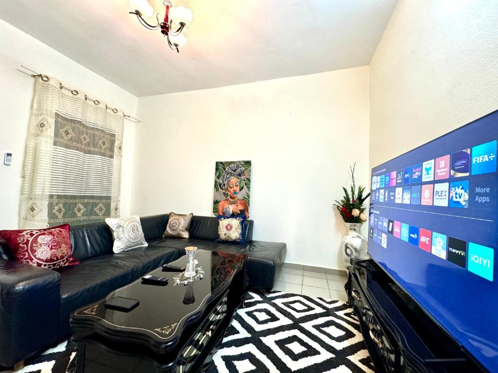 a living room with a black couch and a tv at Big apartment Yaoundé 2 rooms in Yaoundé