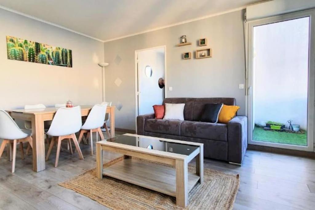 una sala de estar con un sofá y una mesa en Orly Express - Confort à Deux Pas de l'Aéroport, en Orly