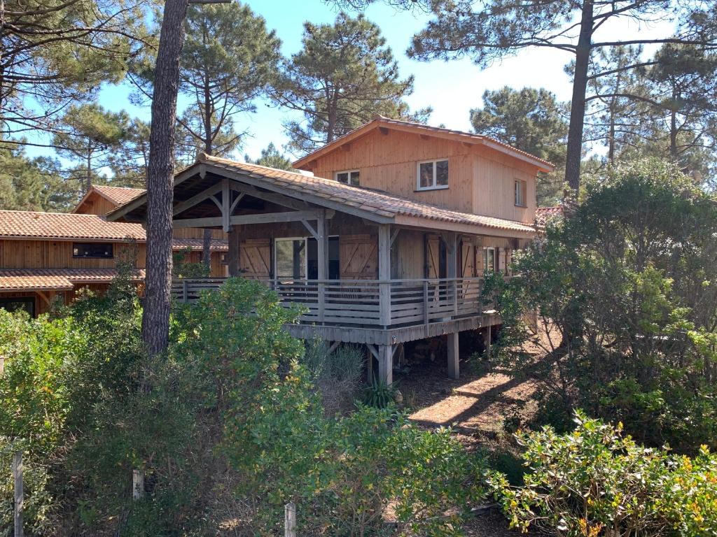 une grande maison avec une terrasse couverte dans les bois dans l'établissement Maison quatre voyageurs, à Maubuisson