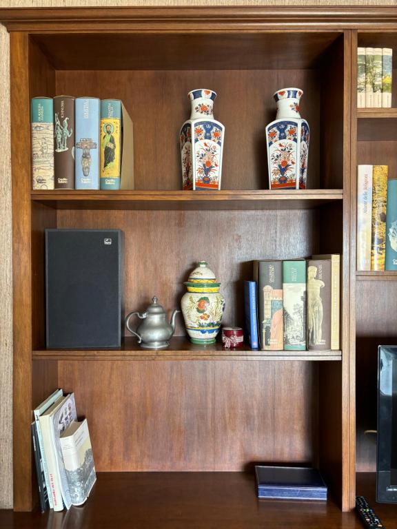 a wooden book shelf with books and vases on it at Casa Cele centro città vista mare in Ventimiglia