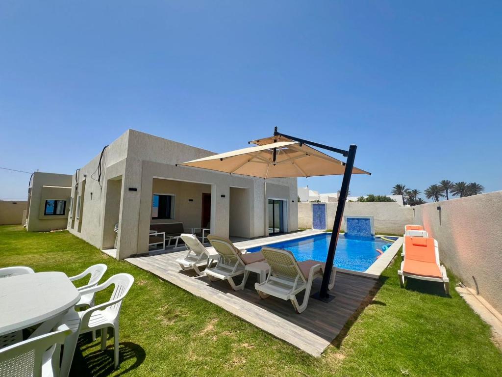 a patio with a table and chairs and an umbrella at Villa Yara in Djerba