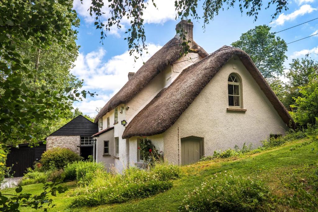 a thatched cottage with a thatched roof at Weeke Brook - Quintessential thatched luxury Devon cottage in Chagford