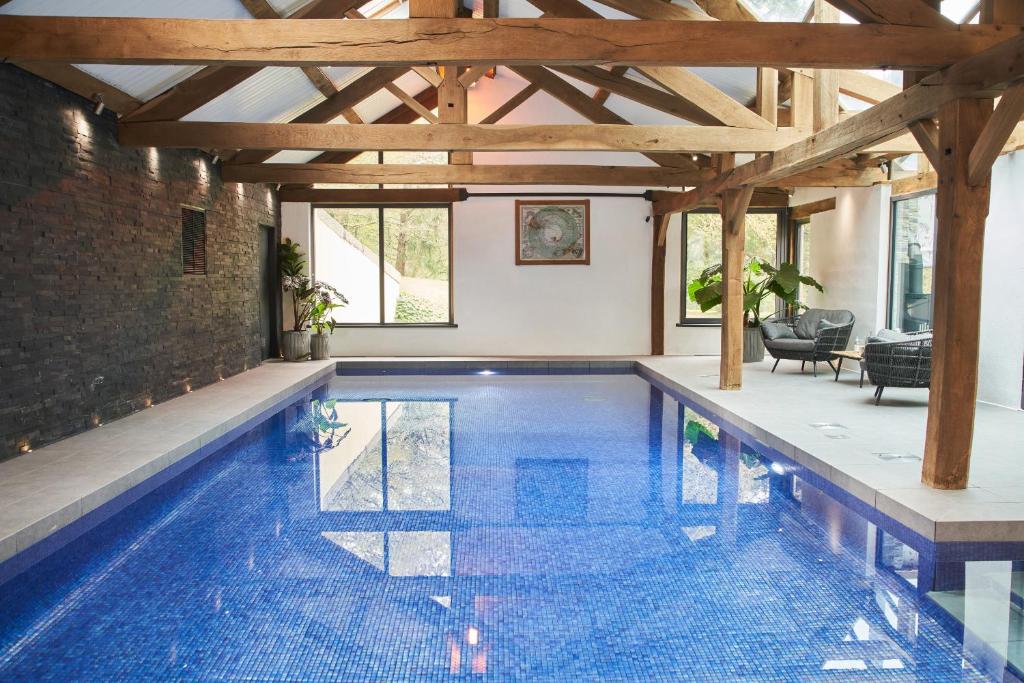 einen Pool in einem Haus mit Holzdecke in der Unterkunft Swifts Return - Apartment with hot tub, sauna and indoor pool (Dartmoor) in Trusham