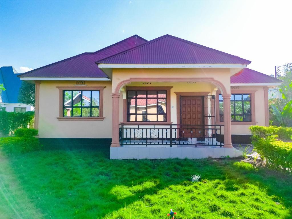 a small house with a green lawn at karibu la kossa in Tuvaila