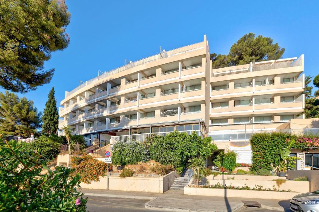 un grand bâtiment blanc avec des arbres devant lui dans l'établissement Résidence Pierre & Vacances Bandol Port, à Bandol