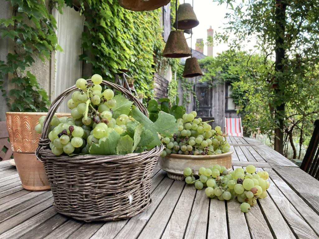 two baskets of grapes sitting on a wooden table at Le 16 maison d'hôtes en Berry in Henrichemont