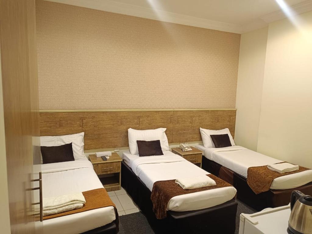 a room with three beds in a room at فندق مناير الاصول in Al Khansāk