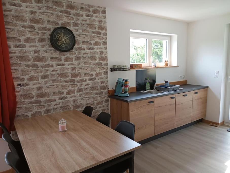 a kitchen with a wooden table and a brick wall at L'elydiane in Hundling