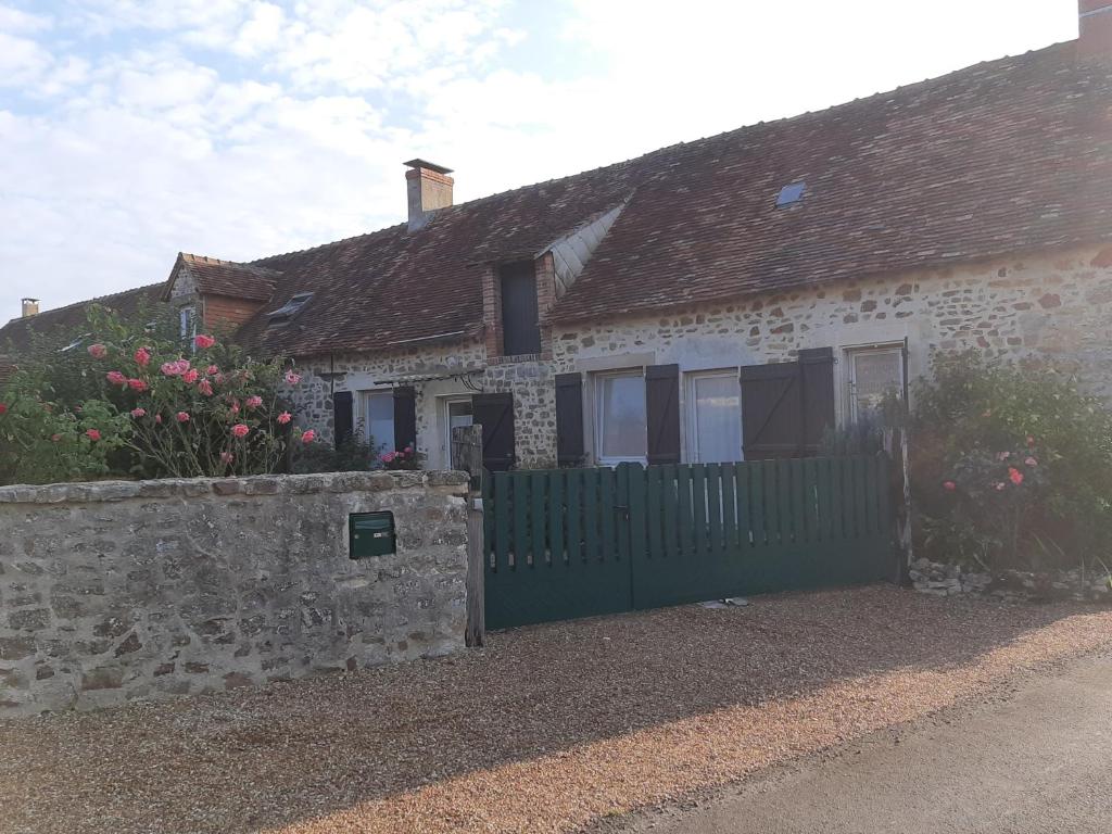 une ancienne maison en pierre avec une clôture verte dans l'établissement gite petit ecotay, à Saint-Symphorien