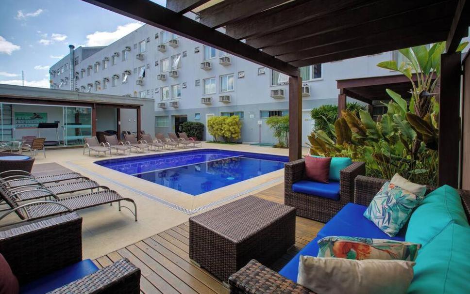 Un patio con piscina y sillas y un edificio. en GoldMen Business Joinville, en Joinville