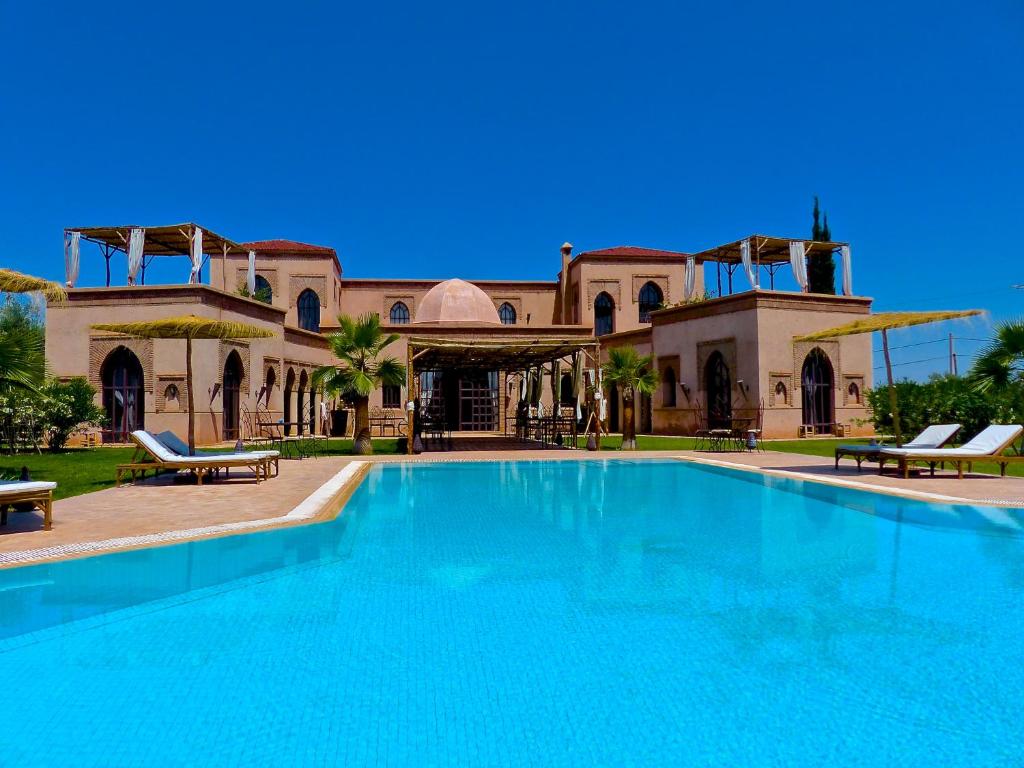 a large swimming pool in front of a building at Le Cazar in El Aïn