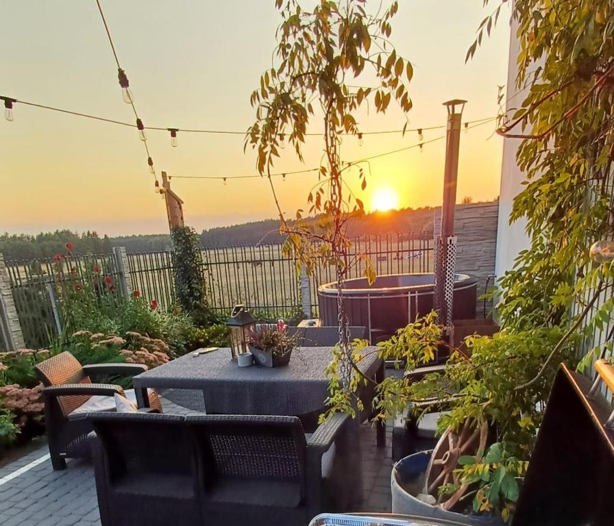 a patio with a table and chairs and the sunset at Agroturystyka "Apartament na wsi" Bory Tucholskie in Szlachta