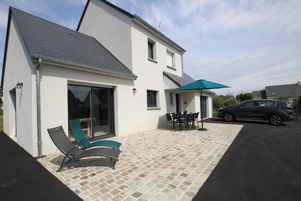 a house with a patio with chairs and an umbrella at La Suretière in Montmartin-sur-Mer