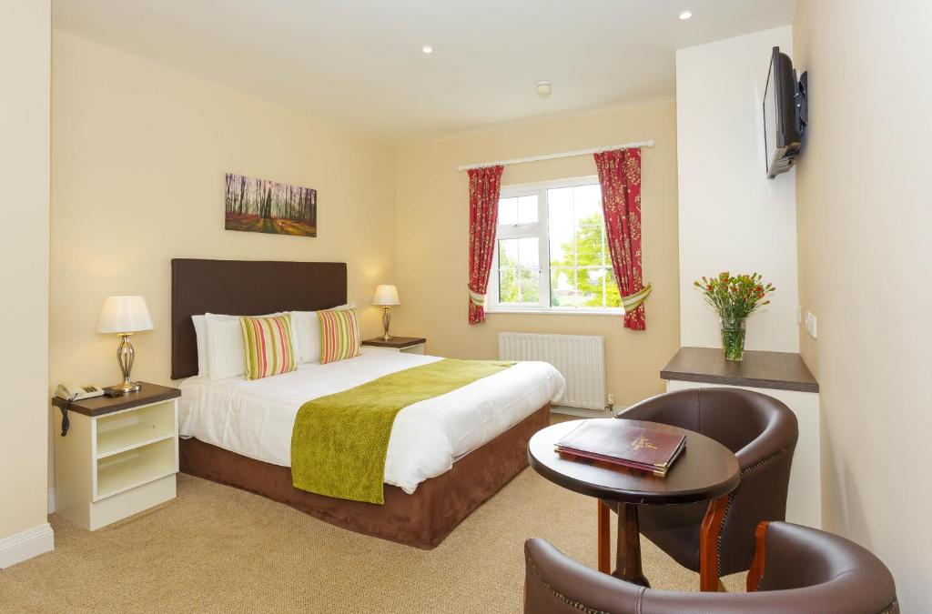 a bedroom with a bed and a table and a chair at Ashville House in Killarney