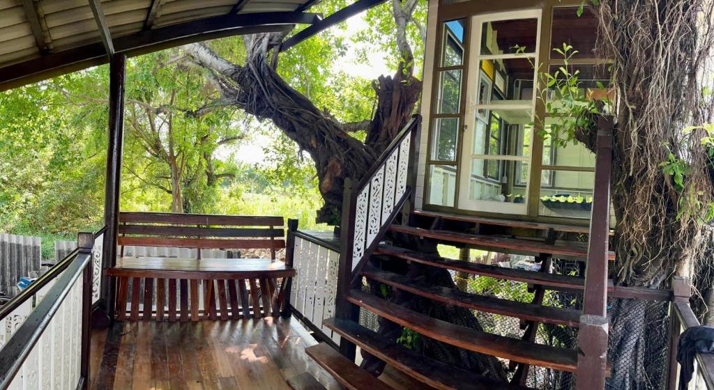 a porch of a tree house with stairs and a window at Croc Camp in Lat Krabang