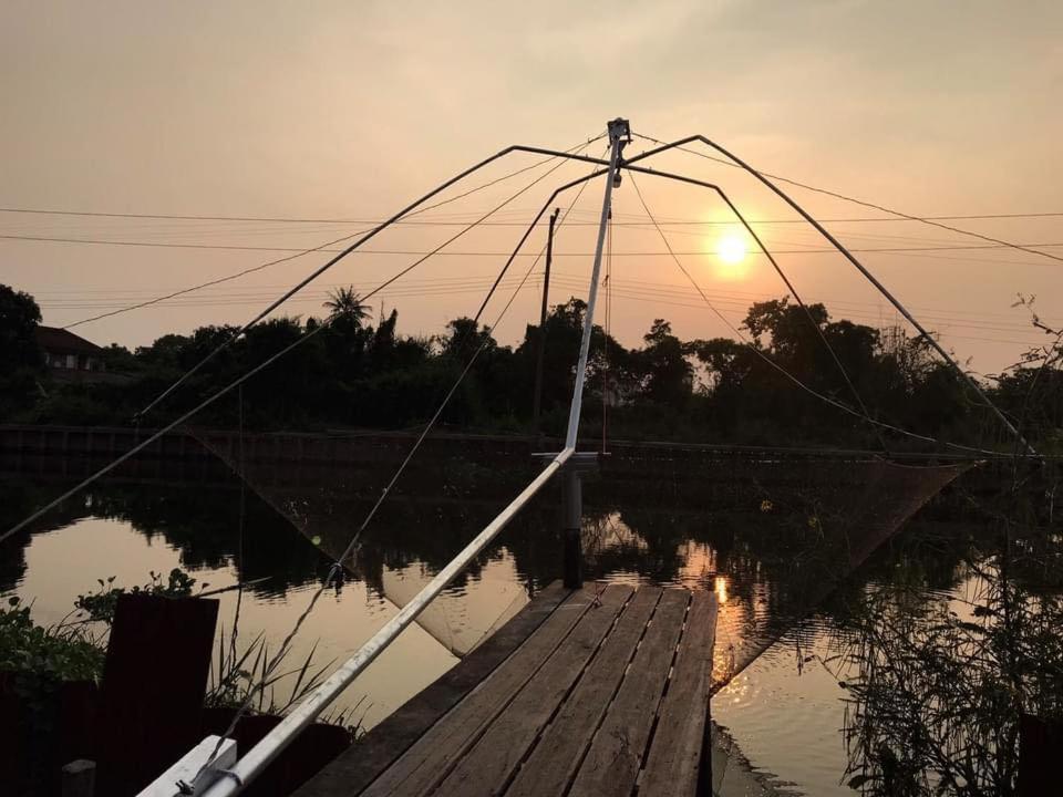 a boat tied up to a dock with the sunset at Croc Camp in Lat Krabang