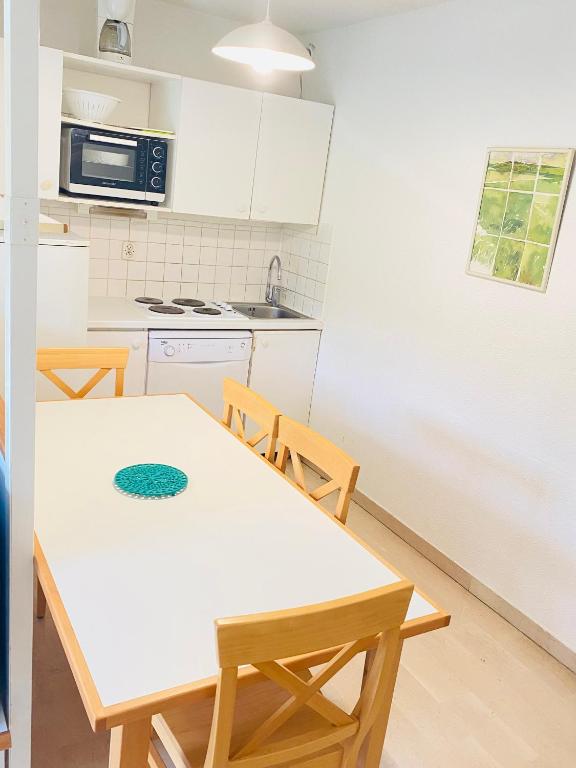 - une cuisine avec une table et des chaises blanches dans l'établissement F3 à Cannes Résidence Villa Livia Pierre et Vacances, à Cannes