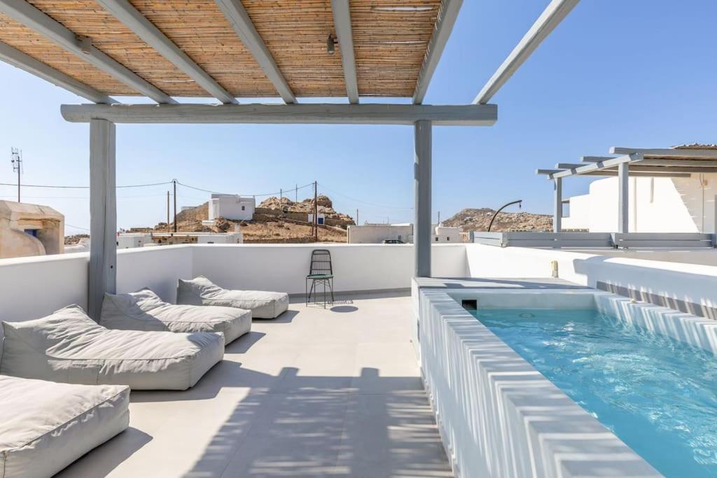 a patio with couches and a swimming pool at Mykonos Luxury Home with Jacuzzi in Kalo Livadi