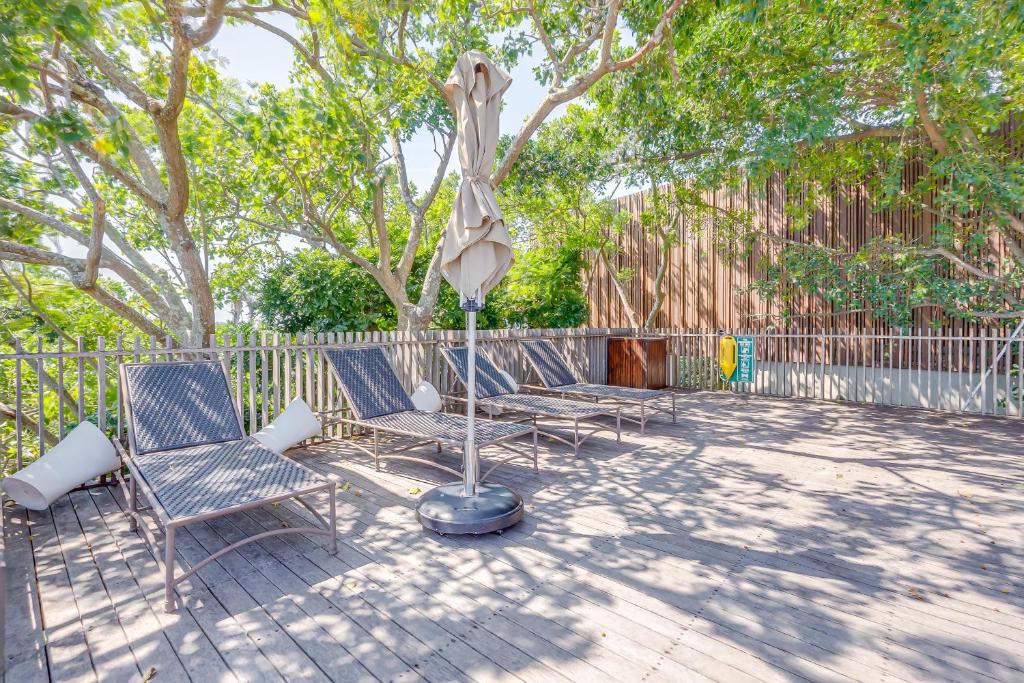 a patio with two chairs and an umbrella at 9 Dash Apartment, Dunkirk Estate in uMhlali