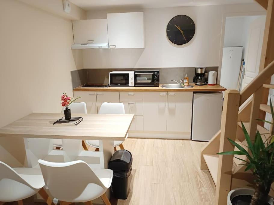 una cocina con mesa y sillas y un reloj en la pared en Le petit cocon, en Pont-lʼÉvêque