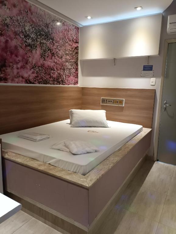 a large bed in a room with a painting on the wall at motel chanty in Piracicaba