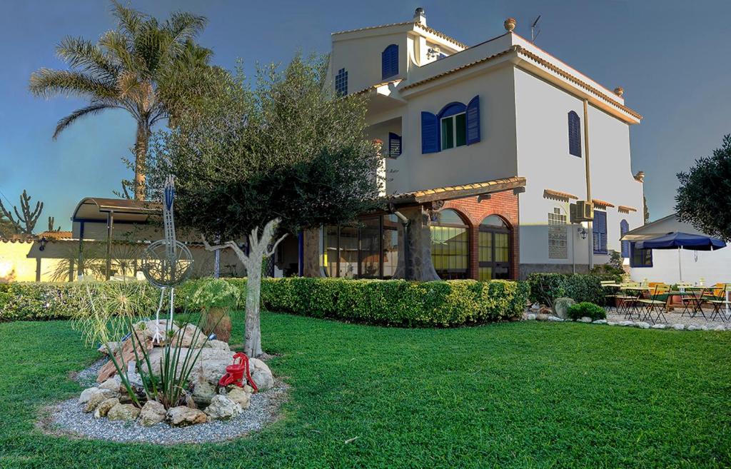 una casa grande con un patio con un árbol en B&B Le Saline, en Siracusa