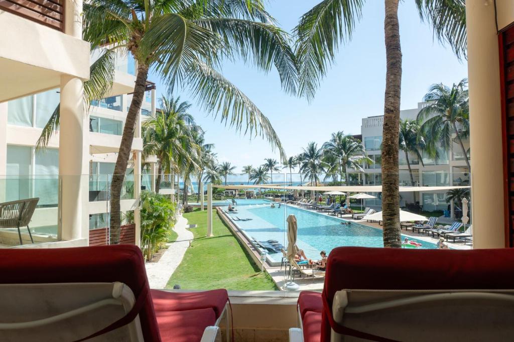 プラヤ・デル・カルメンにあるThe Elements Oceanfront & Beachside Condo Hotelのプールの景色を望むバルコニーが備わります。