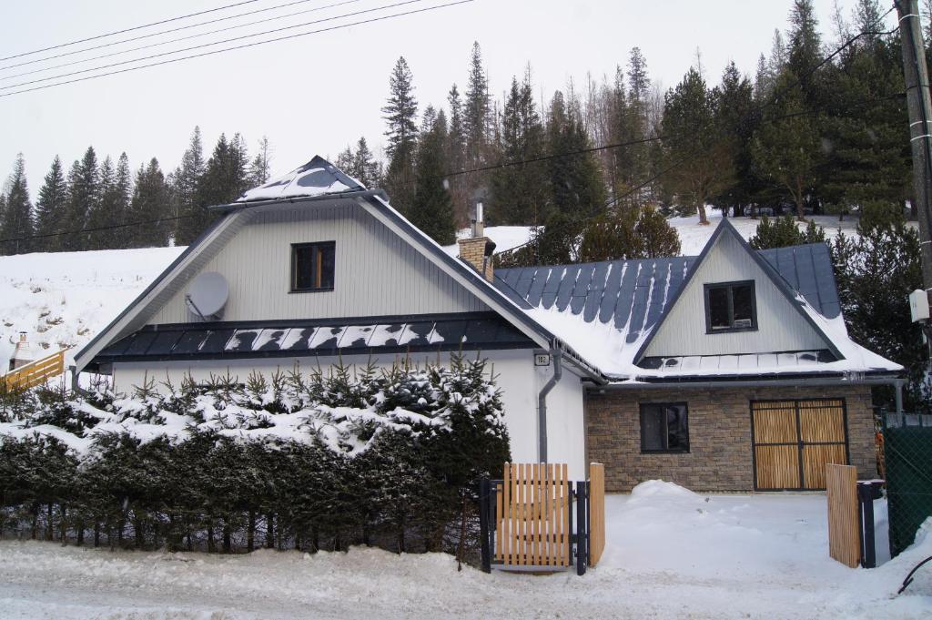 a white house with snow on the roof at WELLNESS Chalet OXY in Ždiar