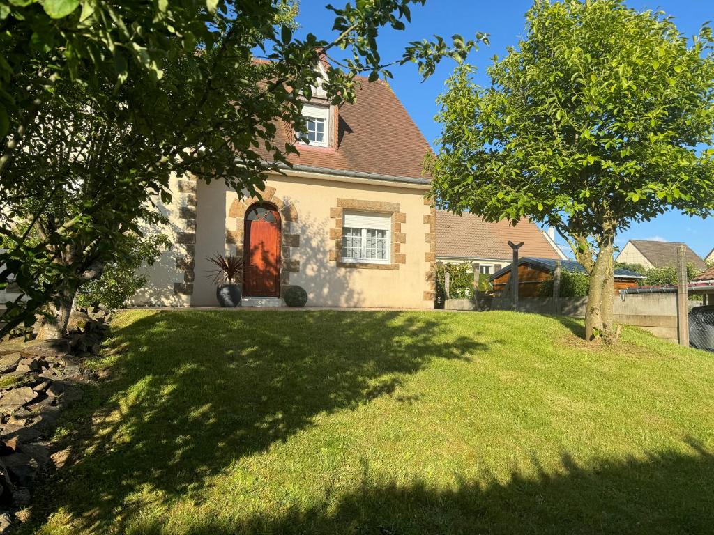 une maison avec une porte rouge sur une cour verdoyante dans l'établissement villa grand standing pour- Basse Normandie - calme dans un cadre verdoyant, à Aubusson