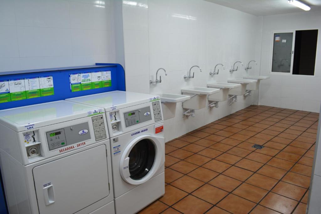 a laundry room with sinks and a washing machine at Camping Valencia el Saler in El Saler