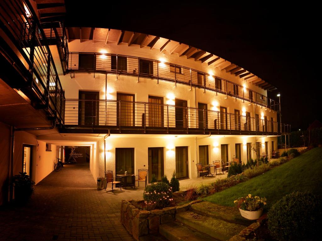 a large white building with a balcony at night at Hotel Restaurant Kohlbrecher Villeroy & Boch SPA in Osnabrück