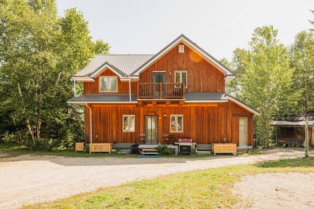 una gran casa de madera con bancos frente a ella en Charming Rustic Chalet on Lac Marie Louise, en Lac-Saint-Paul