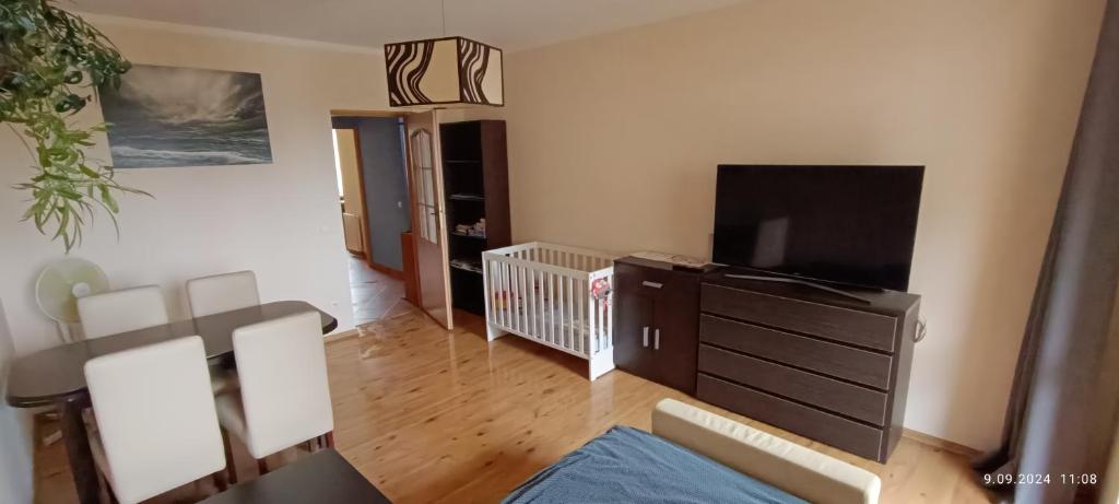 Una sala de estar con una cuna y un televisor de pantalla plana. en Radzikowskiego 100B, en Cracovia